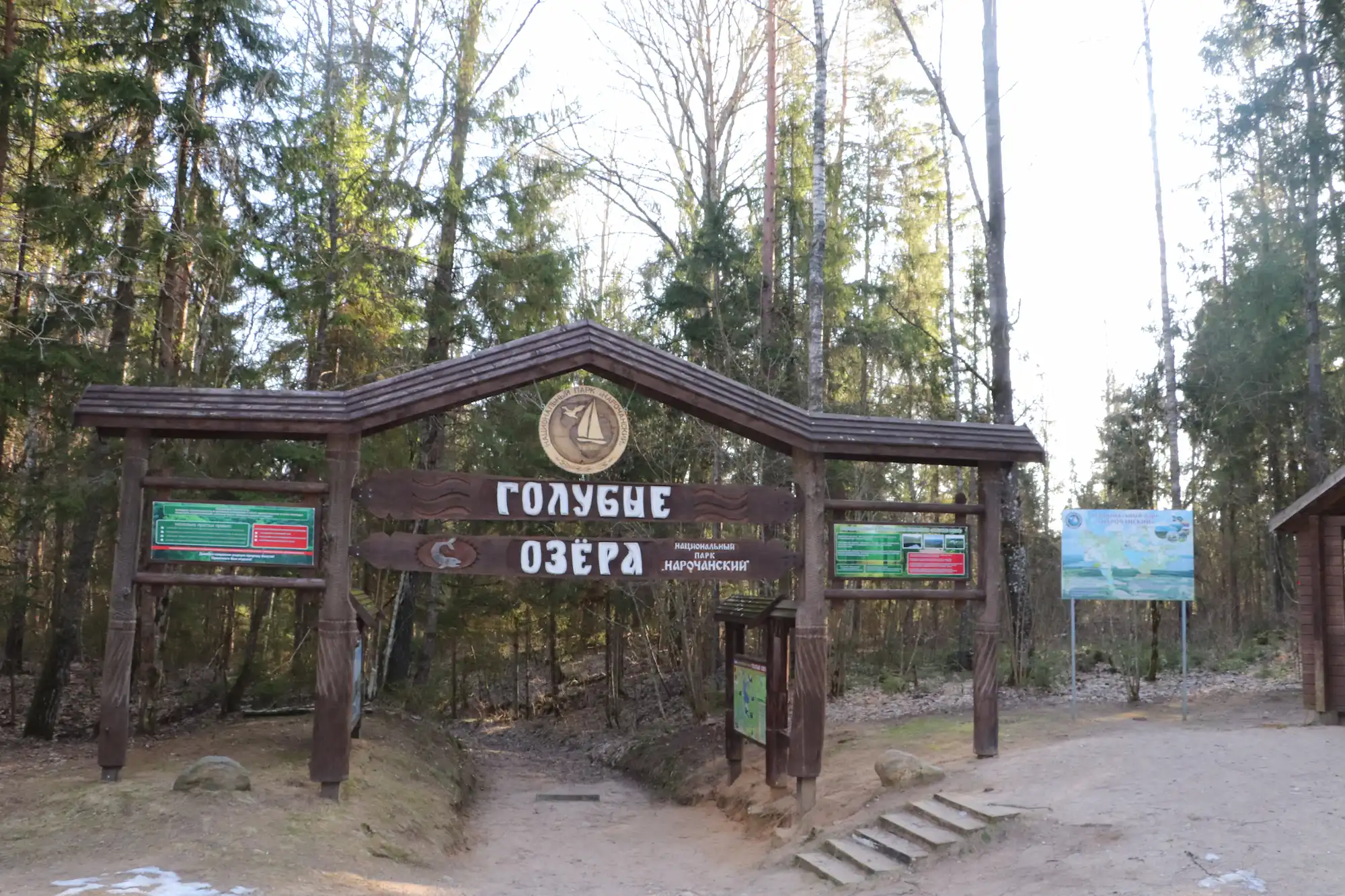 Панорамный вид на информационное табло и лесной массив у озера.
