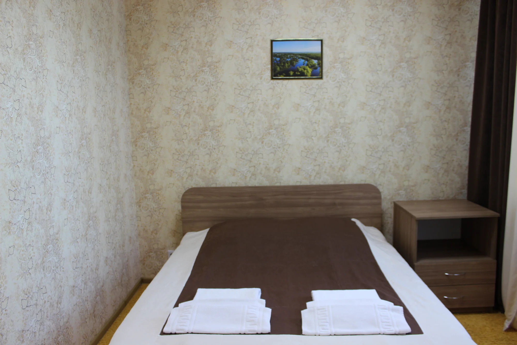 Большая кровать для двоих, застеленная постельным бельем.